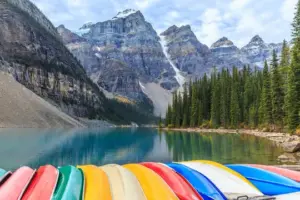 Moraine Lake in Banff National Park, Canada with turquoise water, snow-capped mountains, pine forest, and canoe—top Canadian Rockies travel destination.